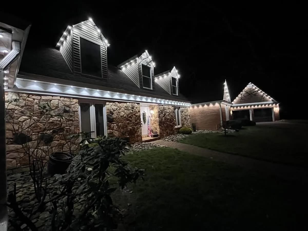 Warm white permanent lighting tracing the rooflines of a stone-front ranch in Hammonton NJ